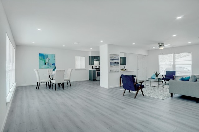 living room featuring ceiling fan, a wealth of natural light, and light hardwood / wood-style flooring