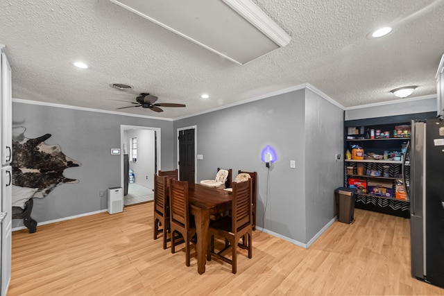 dining room featuring ceiling fan, light hardwood / wood-style floors, a textured ceiling, and crown molding