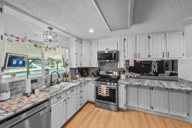 kitchen with stainless steel appliances, a sink, and white cabinets