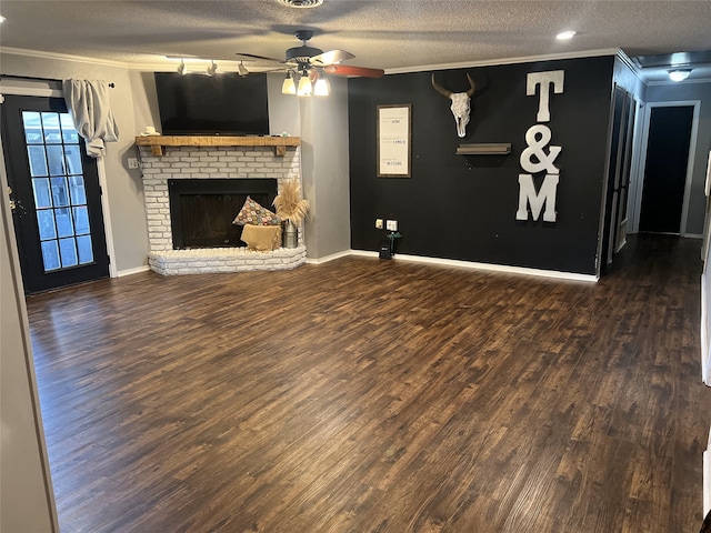 unfurnished living room featuring dark wood finished floors, ceiling fan, a textured ceiling, crown molding, and a brick fireplace