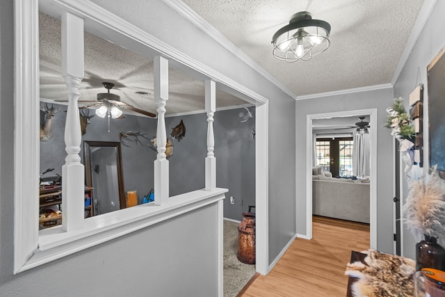 hall with ornamental molding, a textured ceiling, and light hardwood / wood-style flooring