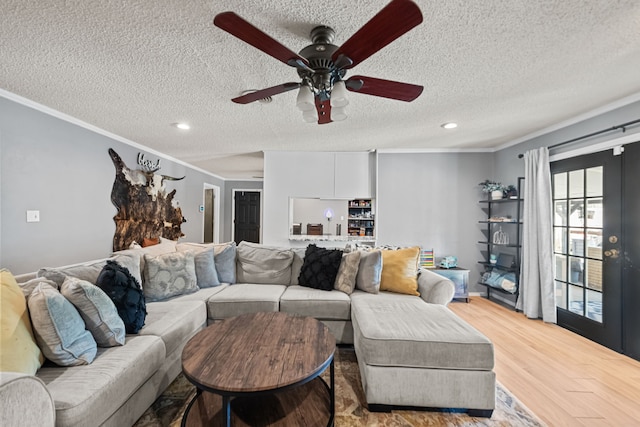 living room featuring a textured ceiling, ceiling fan, crown molding, and light hardwood / wood-style floors