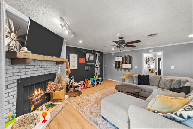 living room with a textured ceiling, a brick fireplace, ornamental molding, and hardwood / wood-style floors