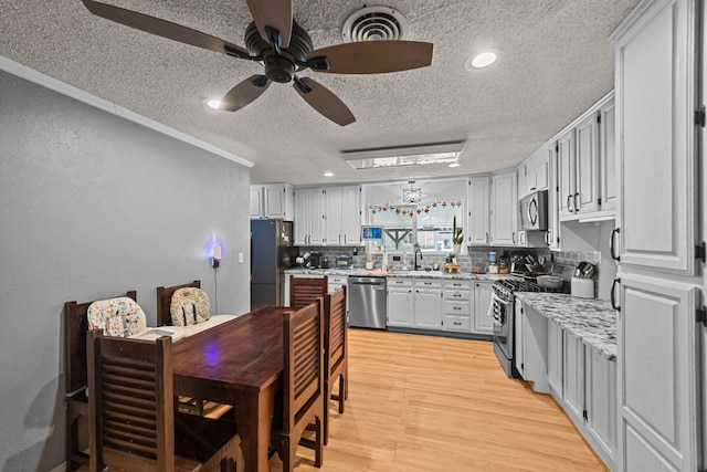 kitchen featuring ceiling fan, tasteful backsplash, sink, light hardwood / wood-style flooring, and appliances with stainless steel finishes