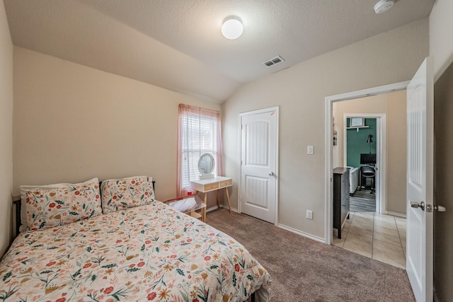 bedroom with lofted ceiling, light colored carpet, and a textured ceiling