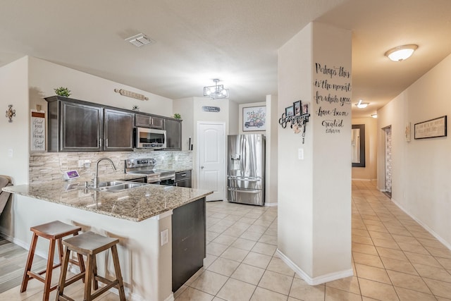 kitchen featuring light stone countertops, appliances with stainless steel finishes, decorative backsplash, sink, and light tile patterned floors