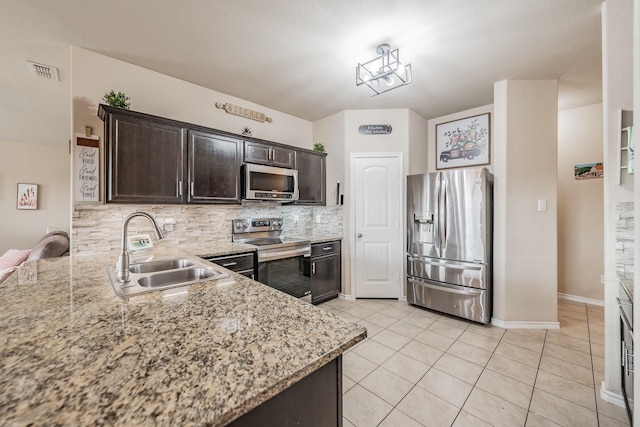 kitchen with appliances with stainless steel finishes, sink, backsplash, light tile patterned floors, and dark brown cabinets