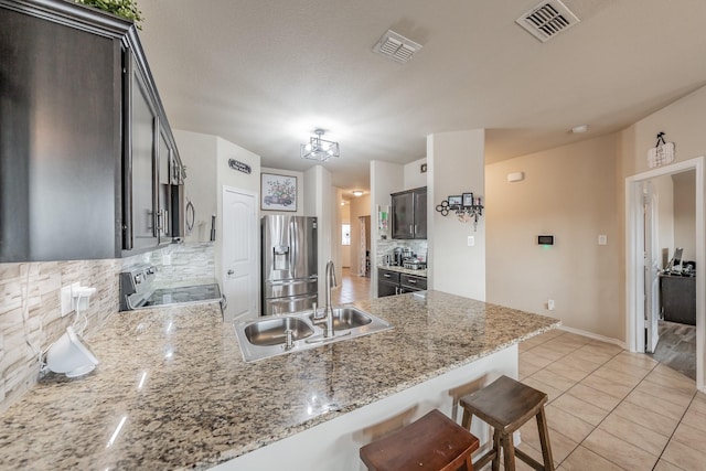 kitchen featuring stainless steel appliances, decorative backsplash, light stone counters, and sink