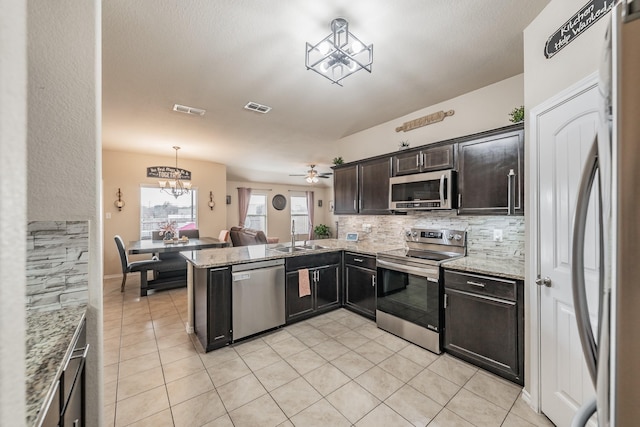 kitchen with ceiling fan with notable chandelier, stainless steel appliances, sink, hanging light fixtures, and kitchen peninsula