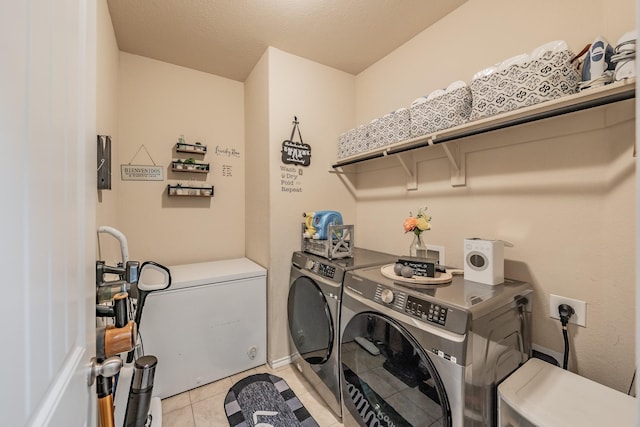 clothes washing area featuring light tile patterned flooring and washer and dryer