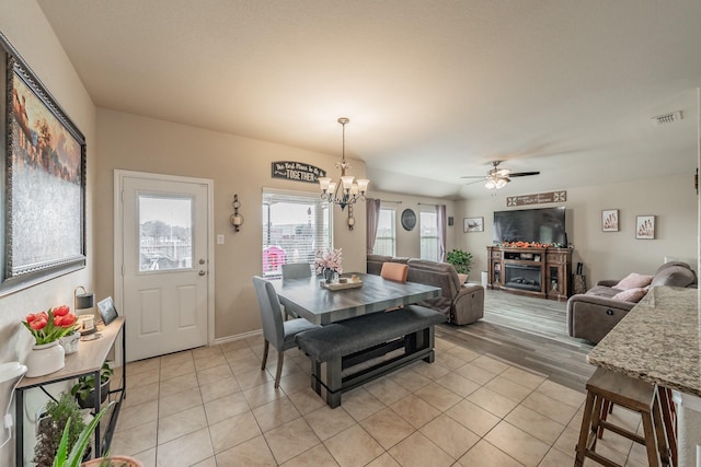 tiled dining area featuring ceiling fan with notable chandelier