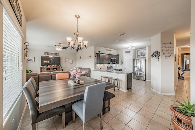 dining space with ceiling fan with notable chandelier and light tile patterned floors