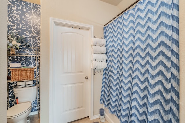 bathroom with toilet, a shower, and tile patterned floors