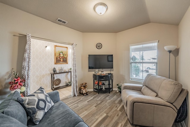 living room featuring light hardwood / wood-style floors, a textured ceiling, and lofted ceiling