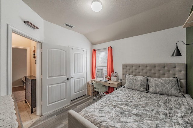 bedroom featuring a textured ceiling, a closet, lofted ceiling, and hardwood / wood-style floors