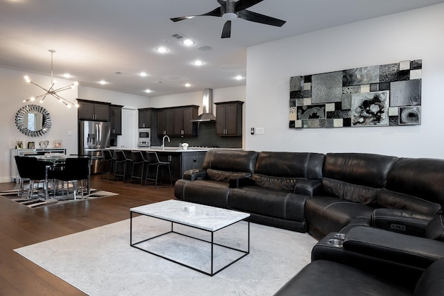 living room with ceiling fan with notable chandelier, sink, and dark hardwood / wood-style flooring