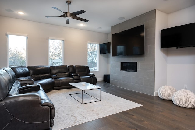 living room featuring a fireplace, ceiling fan, and dark wood-type flooring