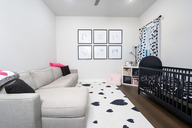 bedroom featuring a nursery area and dark hardwood / wood-style floors