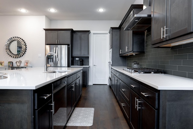 kitchen featuring tasteful backsplash, sink, dark wood-type flooring, stainless steel appliances, and wall chimney exhaust hood