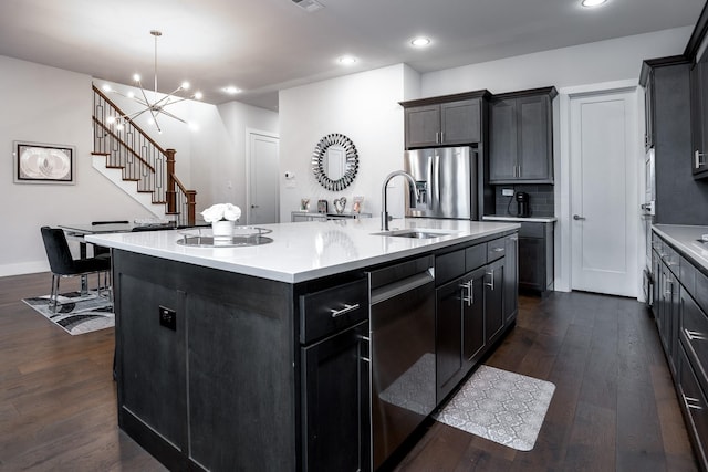 kitchen featuring a center island with sink, appliances with stainless steel finishes, dark hardwood / wood-style floors, a chandelier, and sink