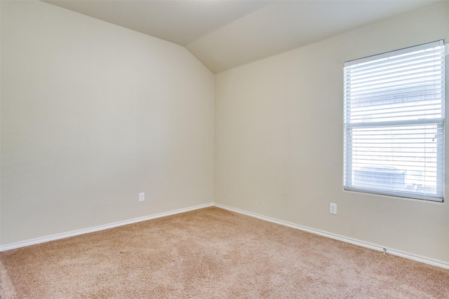 unfurnished room featuring light colored carpet, a healthy amount of sunlight, and vaulted ceiling