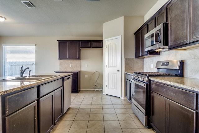 kitchen featuring sink, dark brown cabinets, backsplash, stainless steel appliances, and light tile patterned flooring