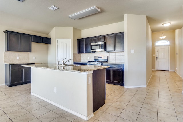 kitchen featuring sink, an island with sink, light tile patterned flooring, and stainless steel appliances