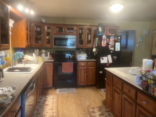 kitchen featuring sink, black appliances, and light wood-type flooring