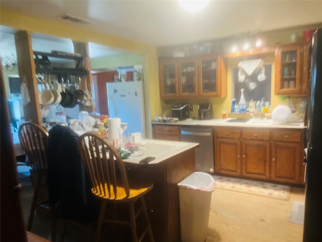 kitchen with light wood-type flooring, dishwasher, white fridge, and black fridge