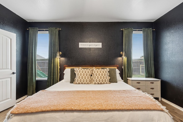 bedroom with hardwood / wood-style flooring and multiple windows