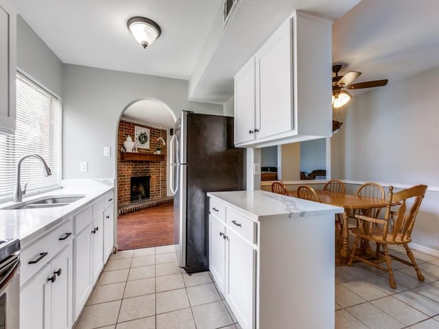 kitchen featuring white cabinets, a fireplace, sink, and light tile patterned flooring