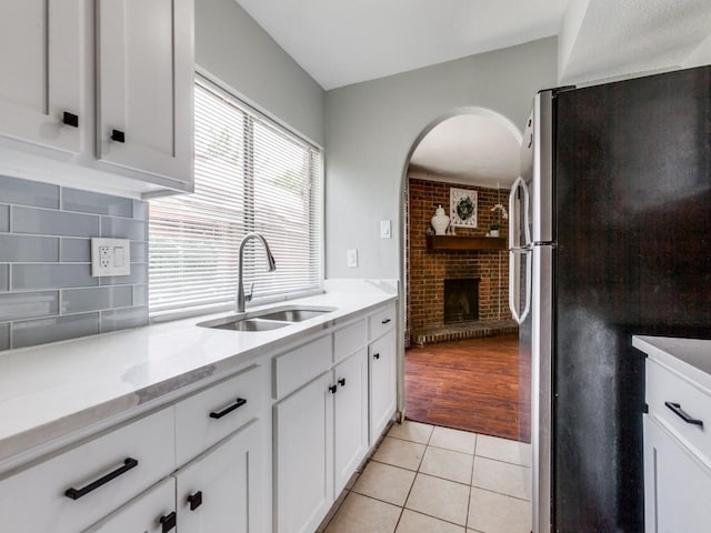 kitchen with light tile patterned floors, stainless steel fridge, sink, and white cabinetry