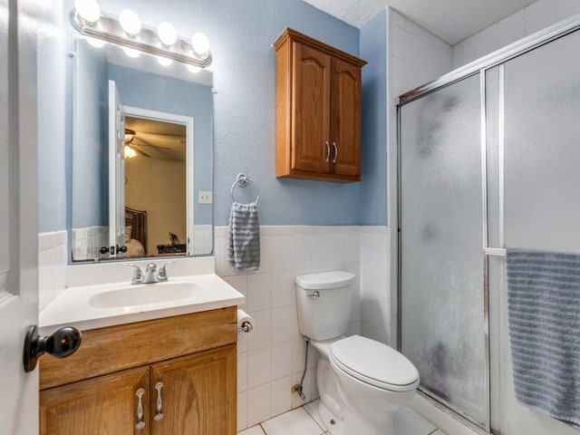 bathroom with toilet, vanity, tile patterned flooring, ceiling fan, and a shower with door