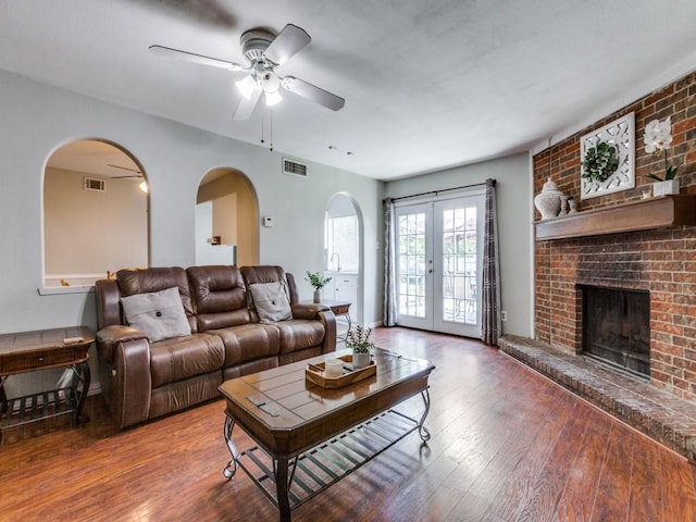 living room with ceiling fan, french doors, a brick fireplace, and hardwood / wood-style floors