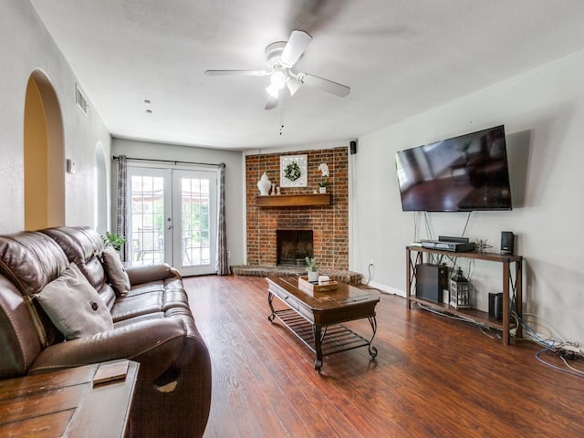 living room with ceiling fan, dark hardwood / wood-style floors, french doors, and a fireplace