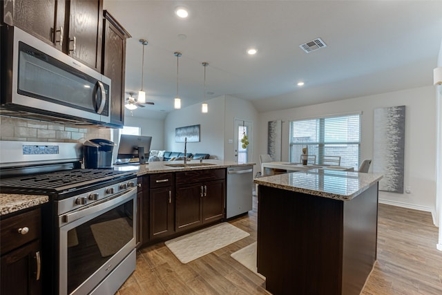 kitchen featuring pendant lighting, appliances with stainless steel finishes, a kitchen island, light hardwood / wood-style floors, and dark brown cabinets