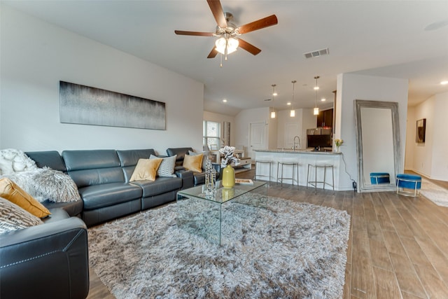 living room featuring ceiling fan, light hardwood / wood-style floors, and sink