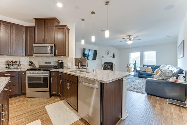 kitchen featuring ceiling fan, pendant lighting, kitchen peninsula, sink, and stainless steel appliances