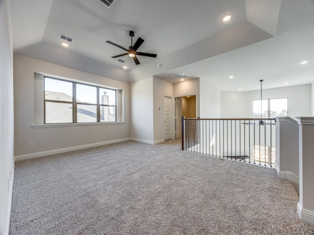 unfurnished room with light carpet, ceiling fan, and a tray ceiling