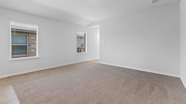 carpeted spare room with vaulted ceiling