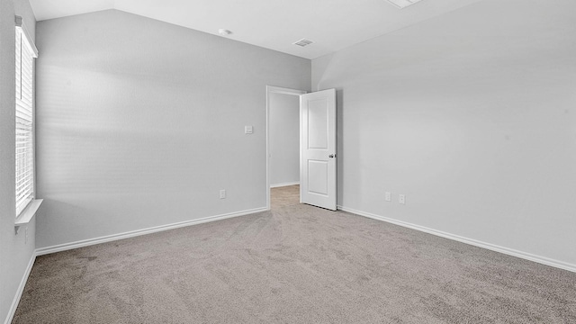 carpeted empty room featuring vaulted ceiling