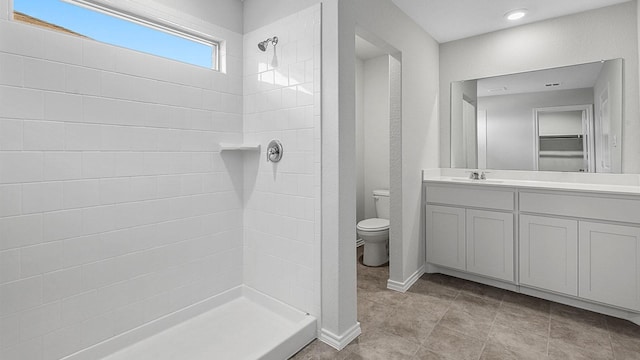 bathroom with tiled shower, vanity, and toilet