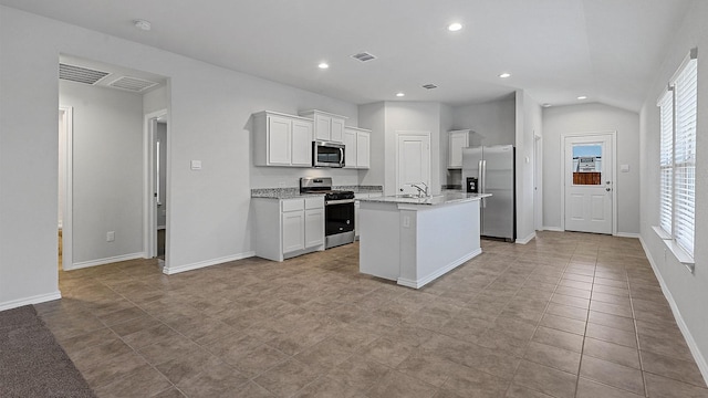 kitchen featuring a center island with sink, stainless steel appliances, light stone countertops, a wealth of natural light, and white cabinets