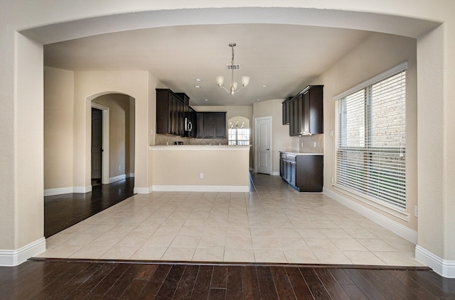 kitchen with dark brown cabinetry, a chandelier, and light wood-type flooring