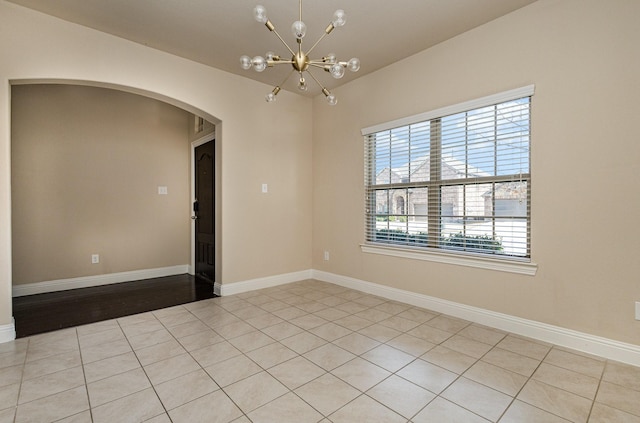 tiled empty room featuring an inviting chandelier