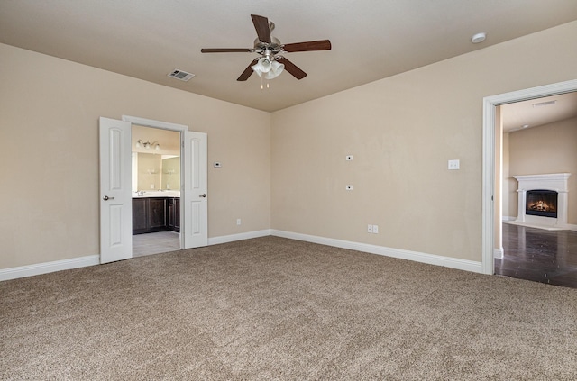 unfurnished bedroom with ensuite bathroom, light carpet, and ceiling fan