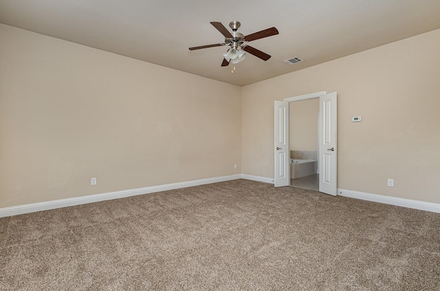 unfurnished bedroom with ensuite bath, carpet floors, and ceiling fan