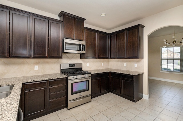 kitchen featuring light stone counters, decorative backsplash, stainless steel appliances, and dark brown cabinetry