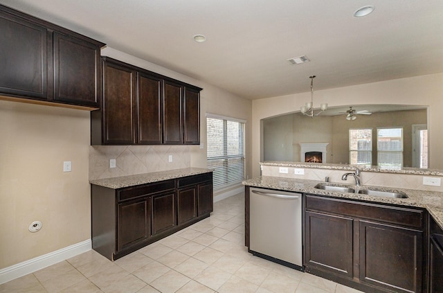 kitchen with light stone countertops, sink, stainless steel dishwasher, and dark brown cabinets