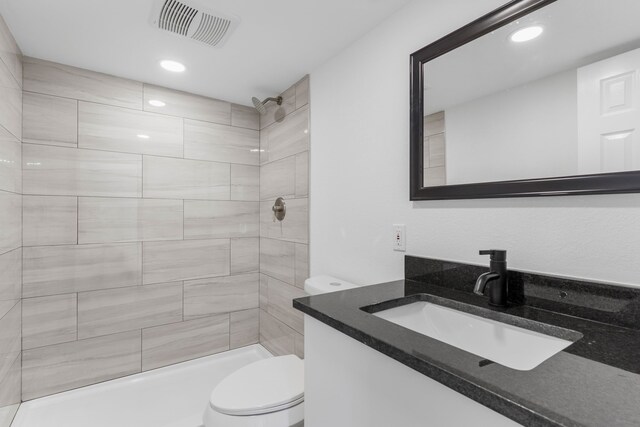 bathroom featuring vanity, toilet, and a tile shower